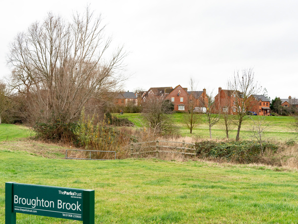 Houses, pond and park sign at Broughton Brook. 