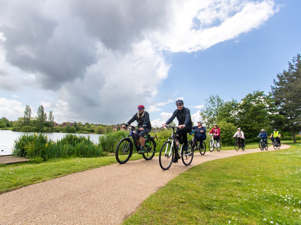 2 cyclists next to a lake with a beautiful sky overhead