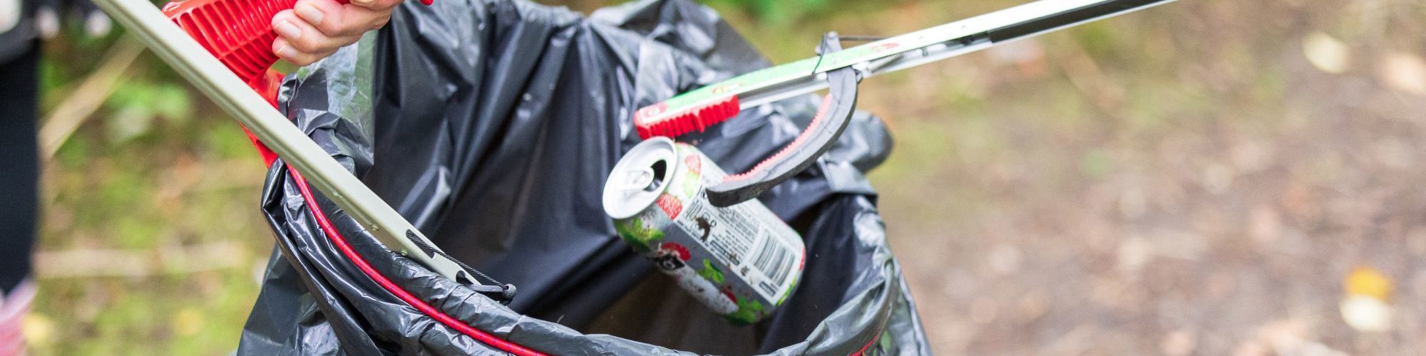 Litter pickers picking up can and dropping into black bin bag