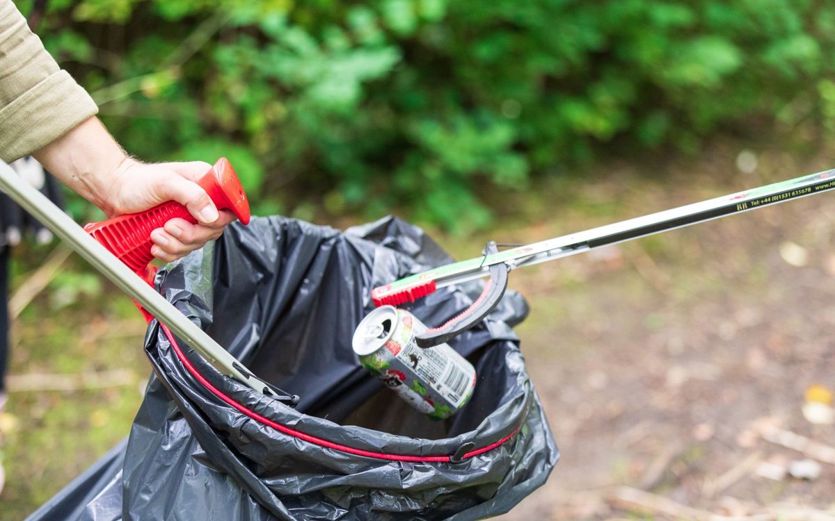 Litter pickers picking up can and dropping into black bin bag