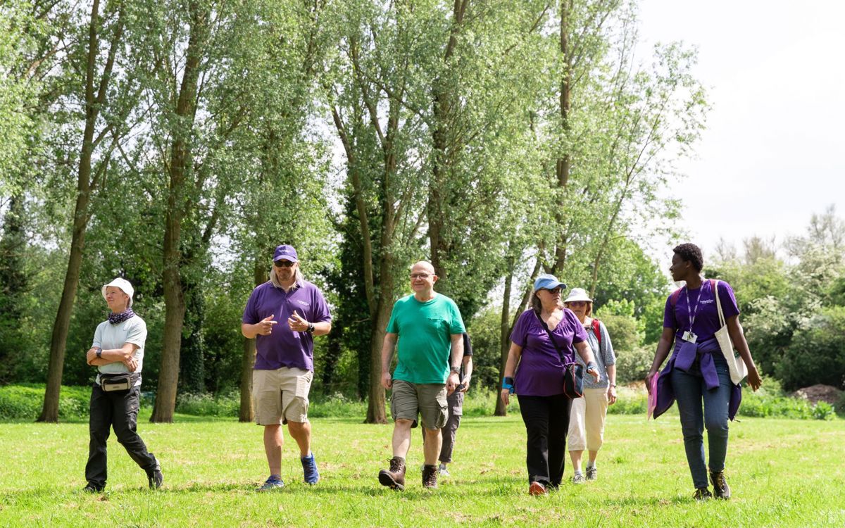 Group of people walking through a park with Parks Trust staff in purple uniform