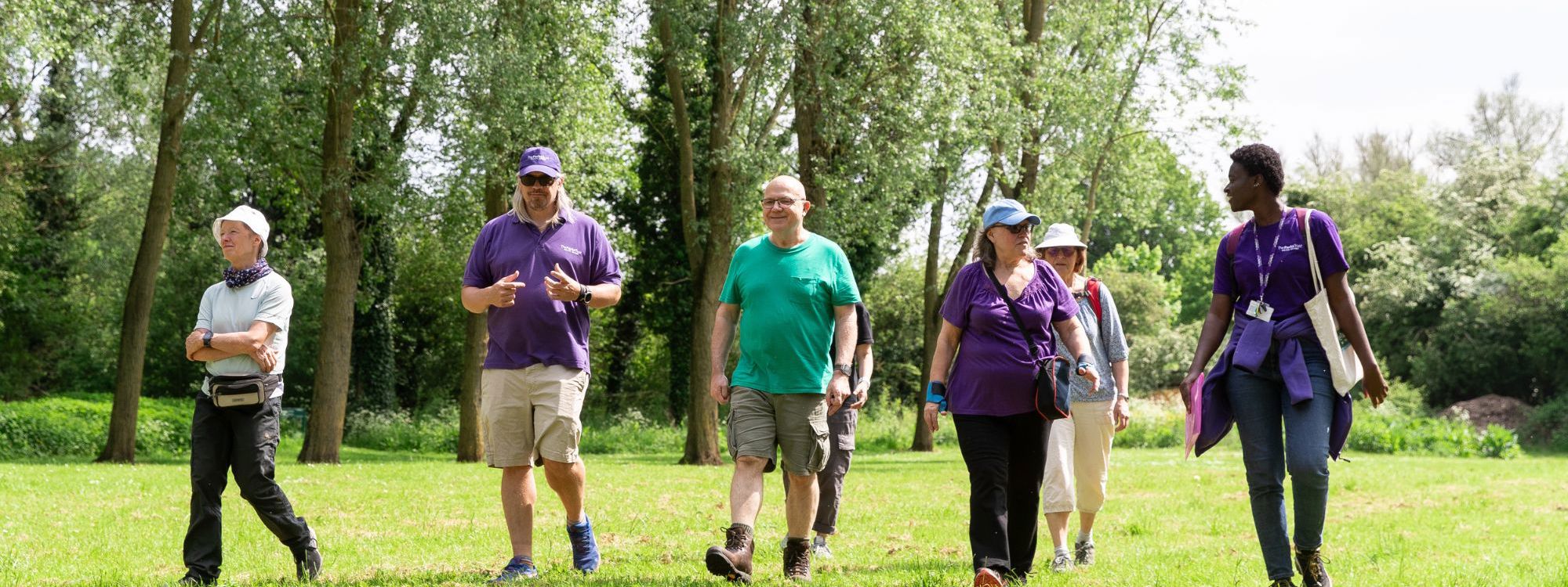 Group of people walking through a park with Parks Trust staff in purple uniform