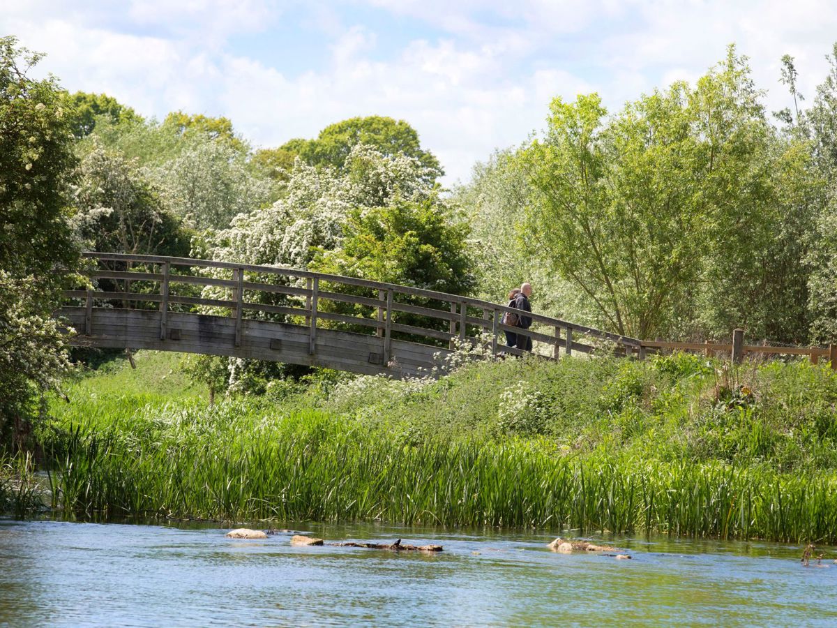 People crossing wooden bridge across river