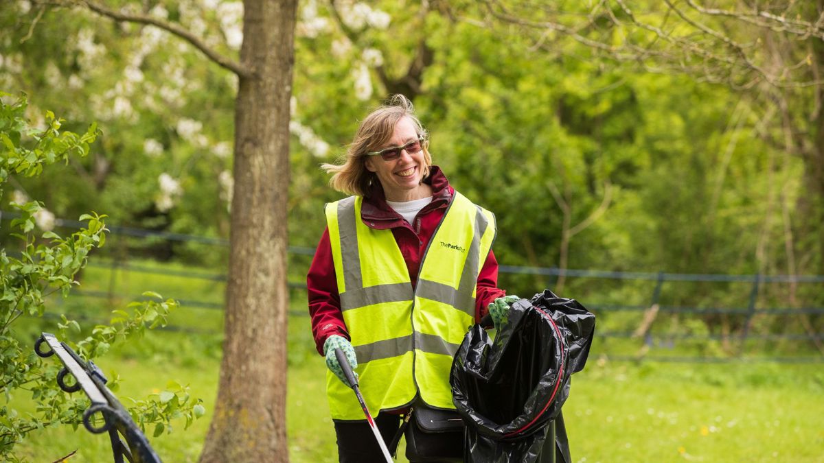 Person litter picking in the park holding waste bag