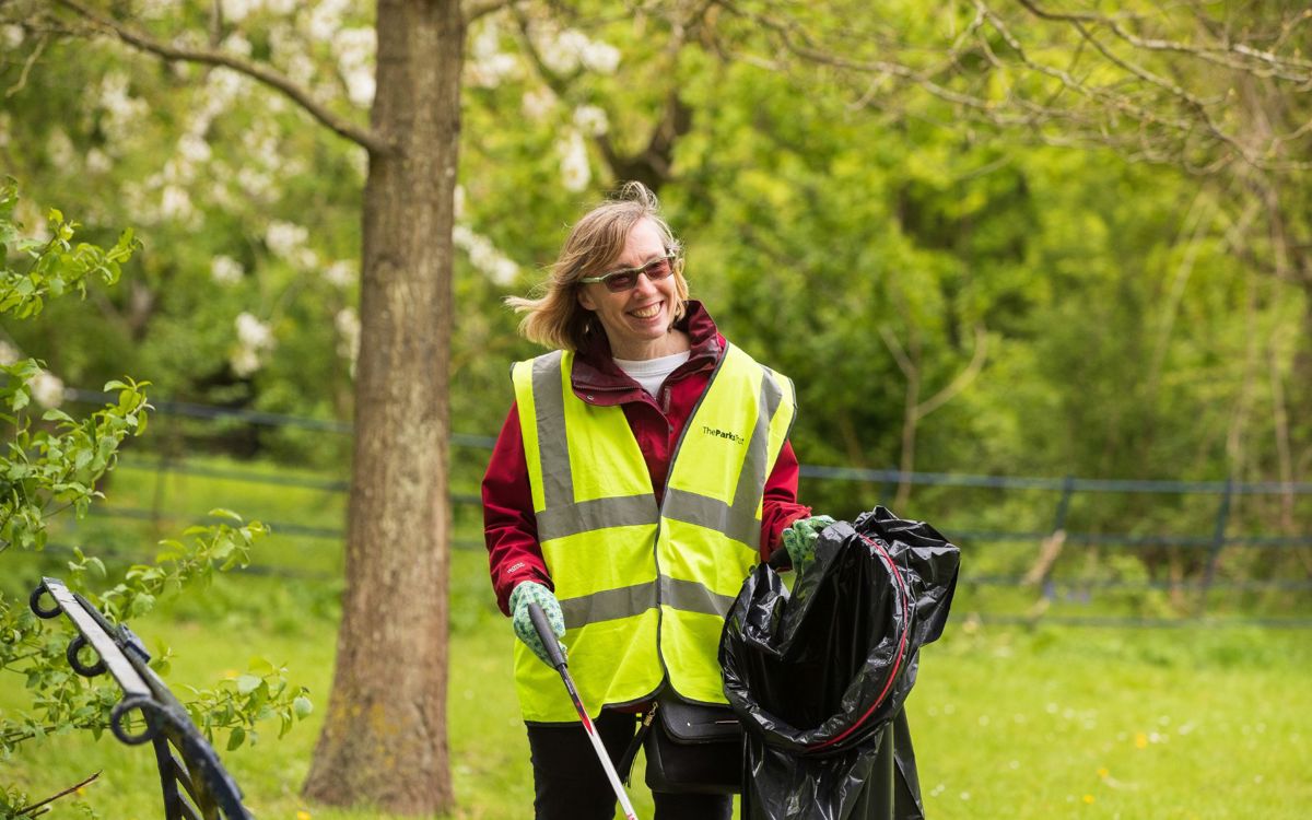 Person litter picking in the park holding waste bag