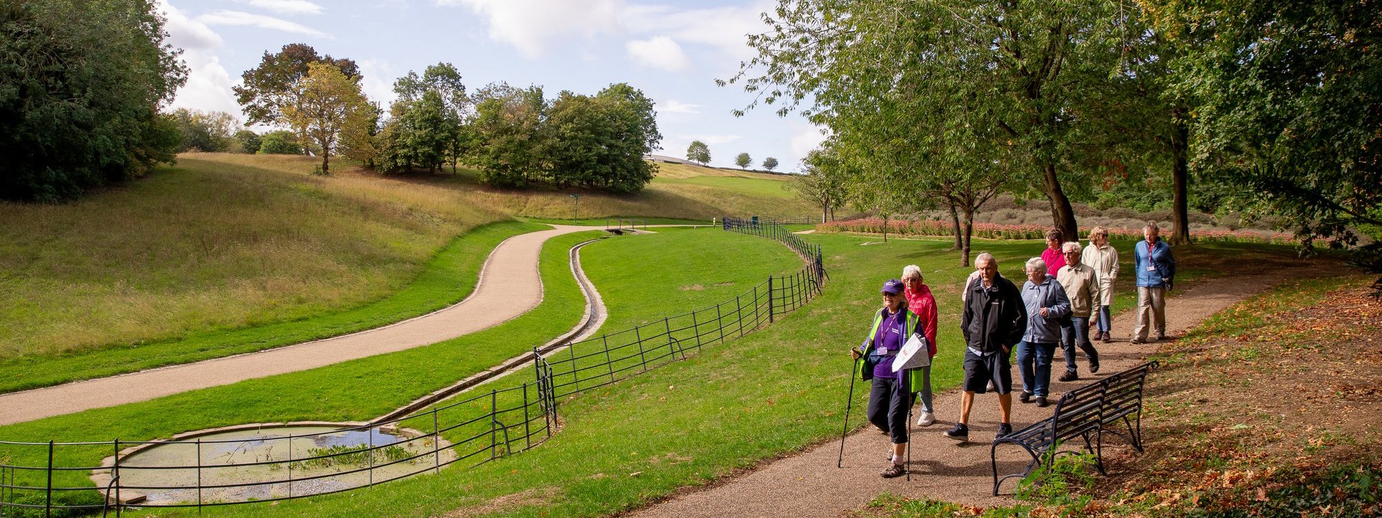 Group of people walking down path in Campbell Park with autumn leaves on the ground