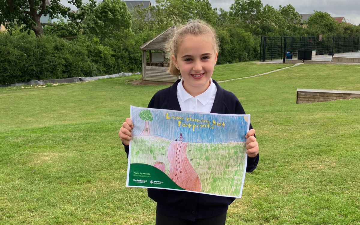 Child outside holding poster with "Leave nothing but footprints on it"