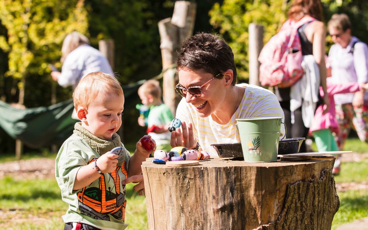 Adult and toddler playing on wooden stump