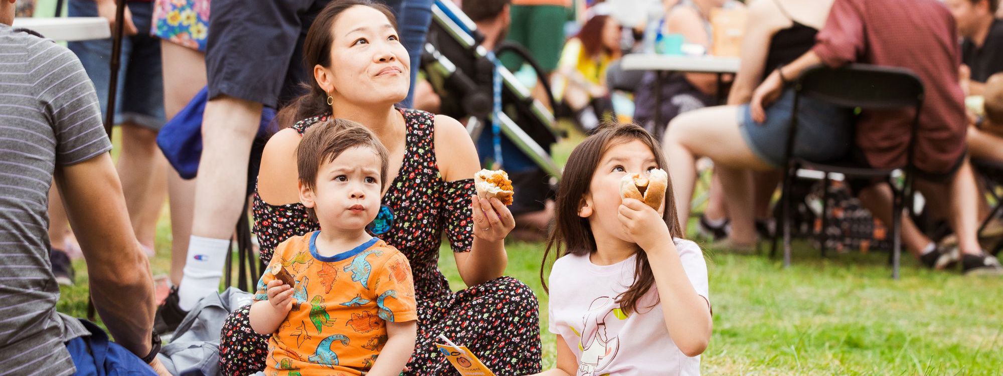 A young family sat on a picnic blanket enjoying some snacks