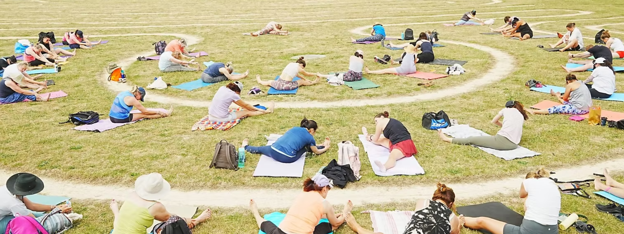 Multiple people doing yoga by the labyrinth at Willen Lake North.