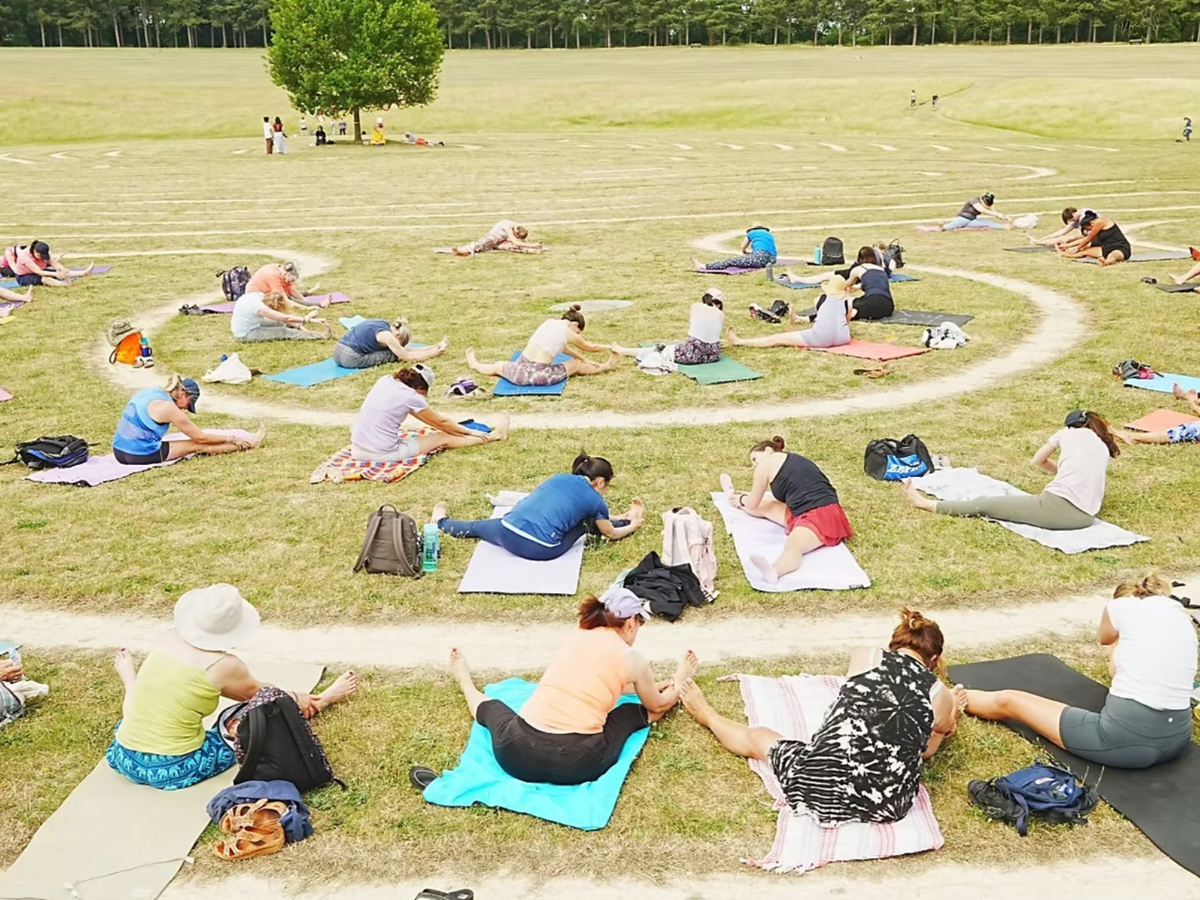 Multiple people doing yoga by the labyrinth at Willen Lake North.