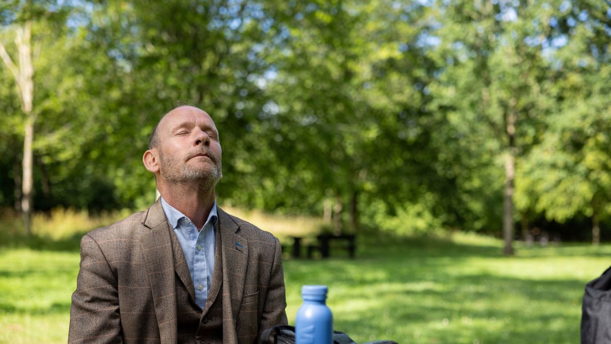 Man with closed eyes head upwards in a park