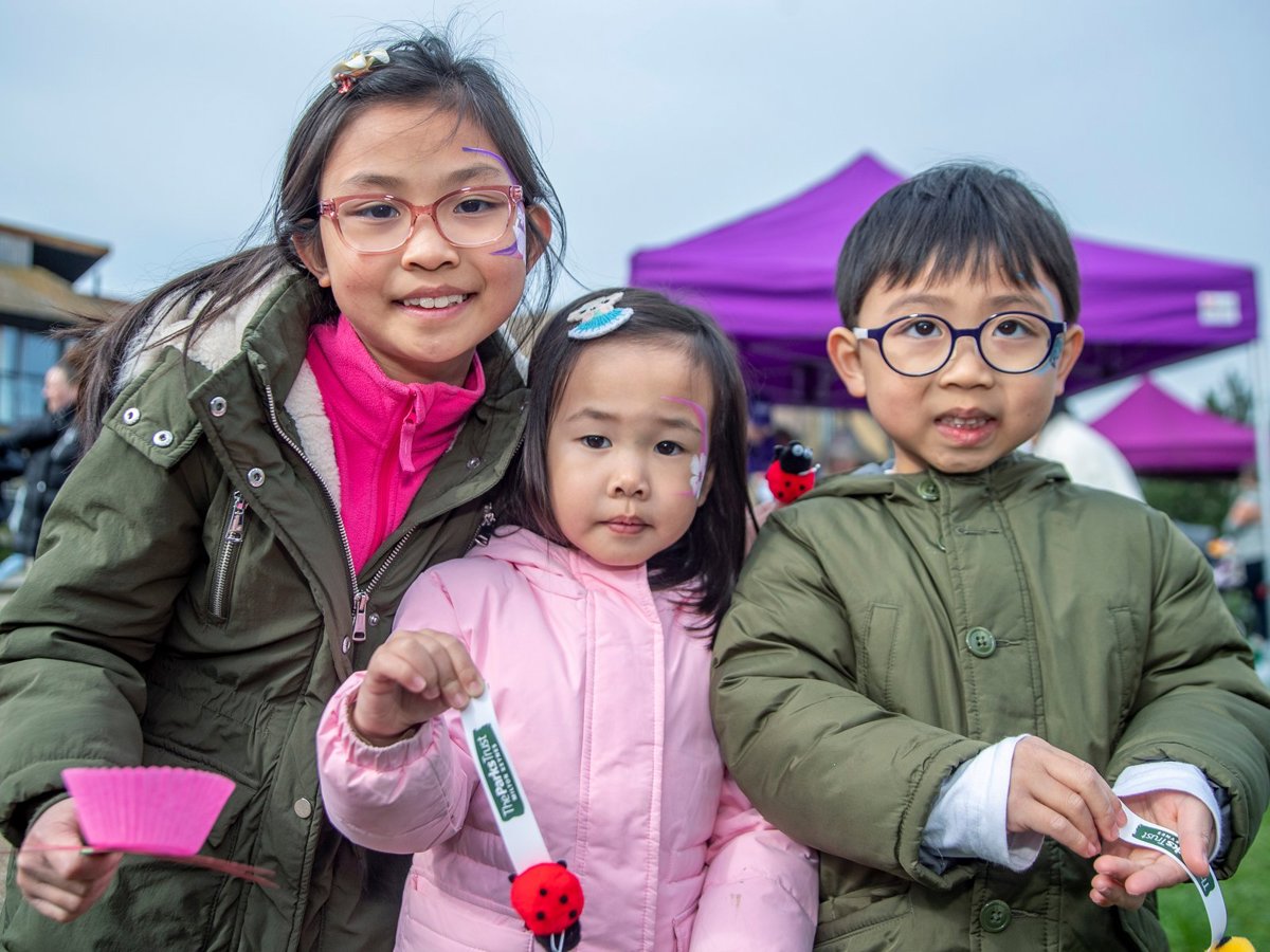 Three children at an outdoor event smiling at the camera