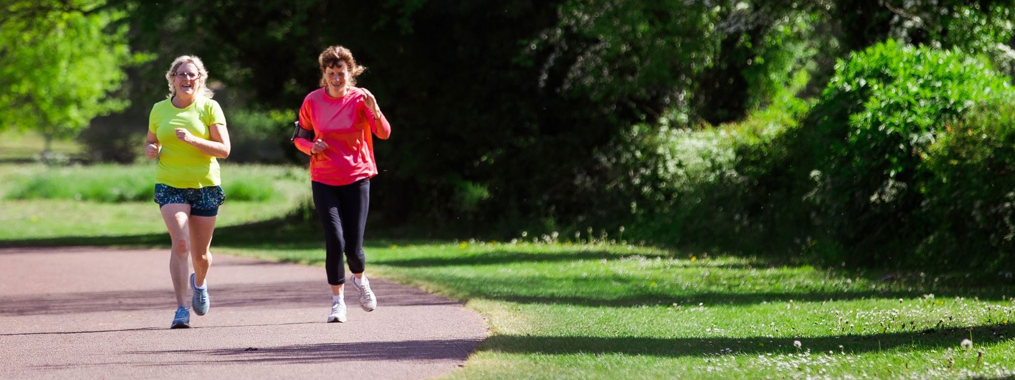 Two people running along Willen Lake path