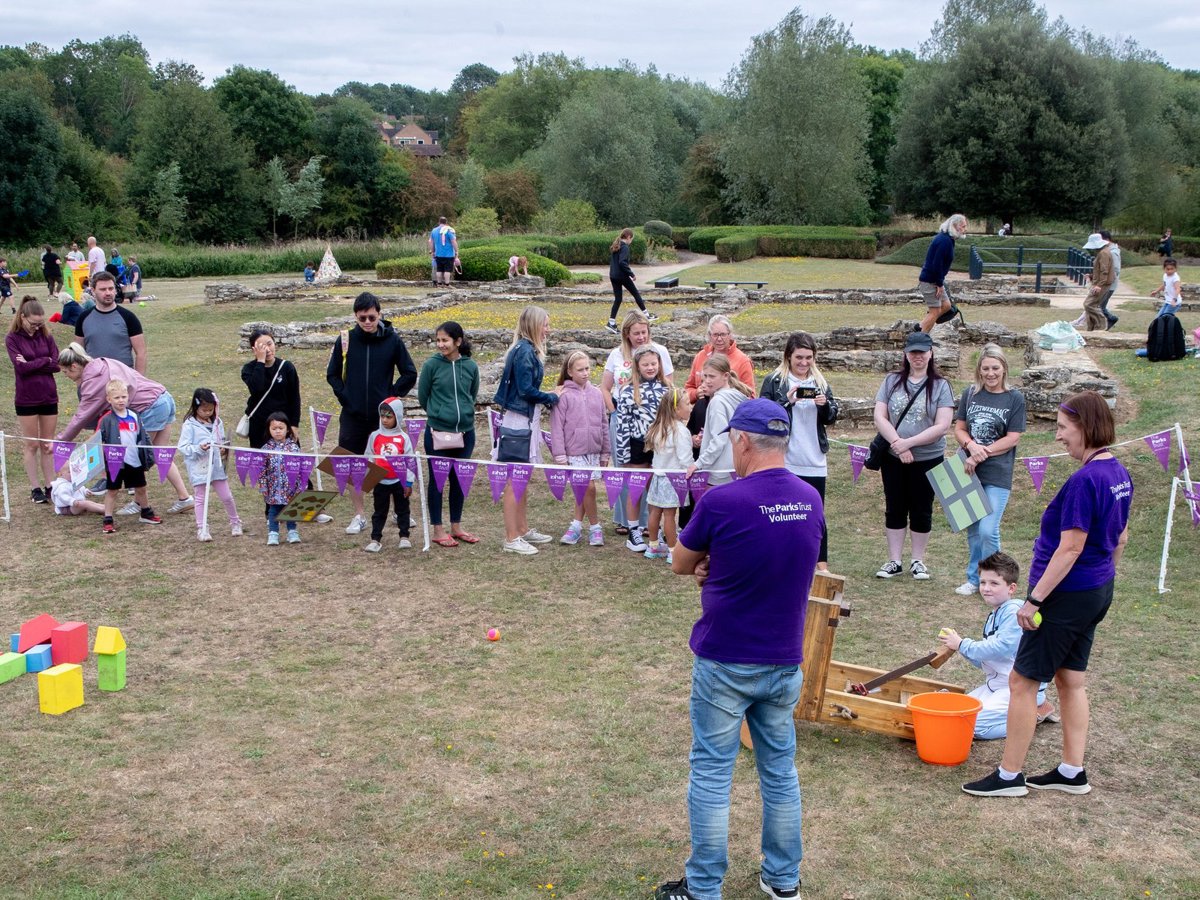 Volunteers running an activity in front of the Roman Villa site, where children can use a roman catapult model to knock foam bricks over.