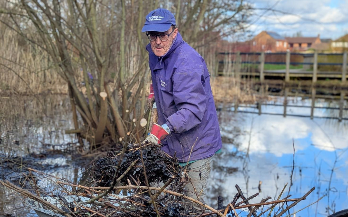 Volunteer shoveling debris from pond
