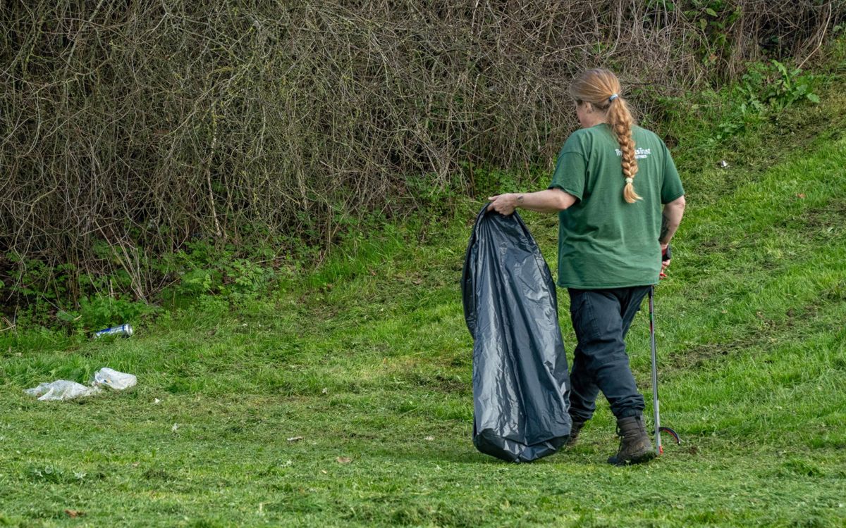 Litter Cleansing Operative with litter picker and bin bag removing litter from the park