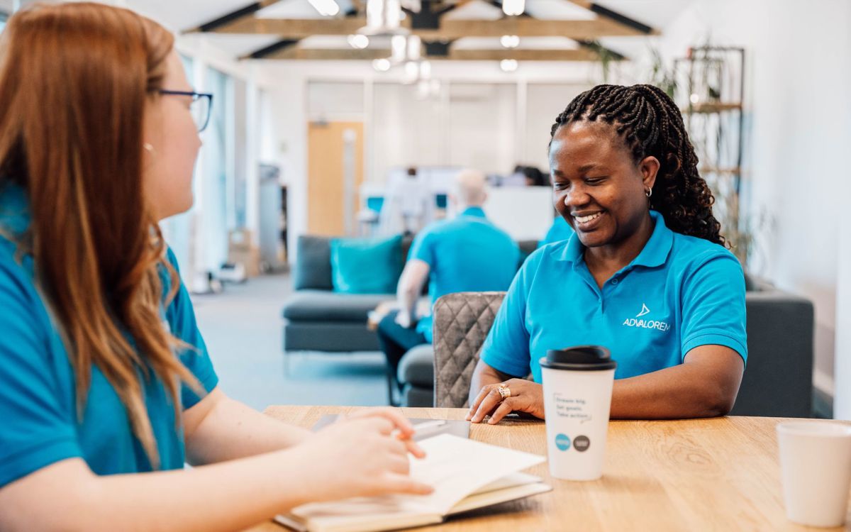 Ad Valorem Staff in blue uniform sat at table talking