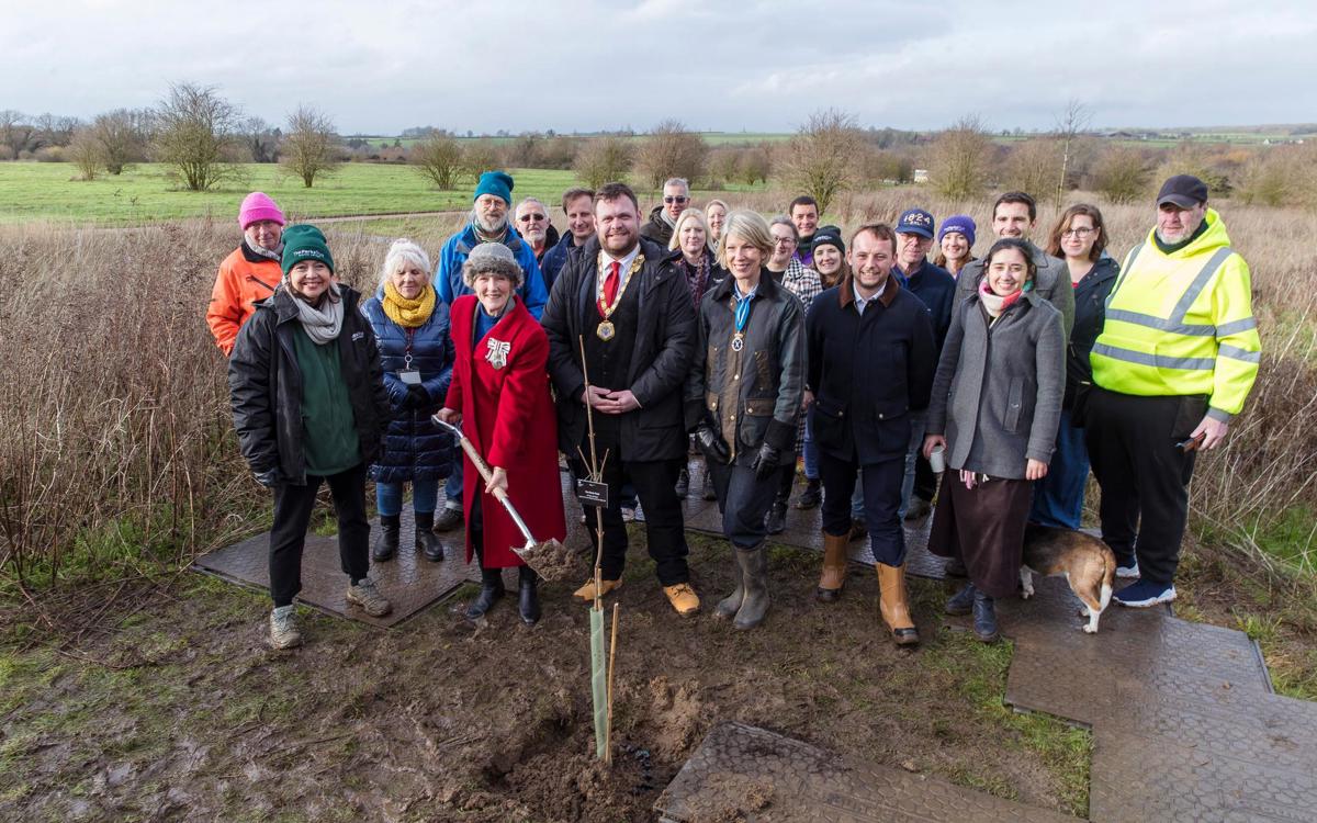Group of diginatries standing in park landscape with tree in ground with mud