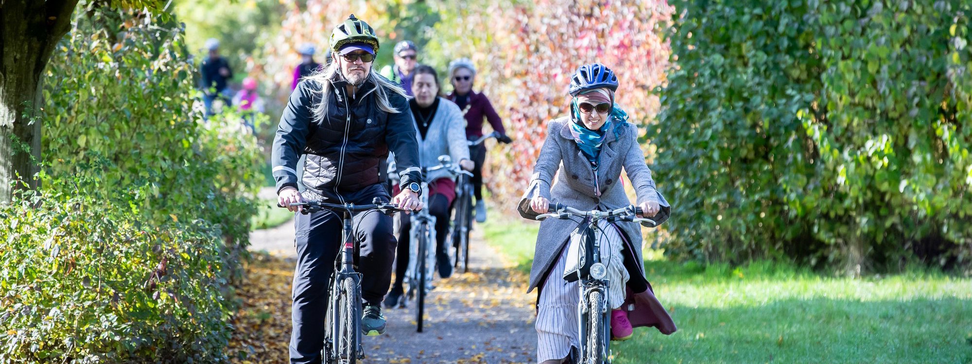 Cyclists cycling towards the camera in a parkland scene 