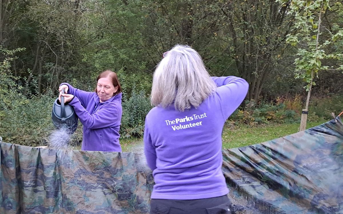 Two Parks Trust volunteers in purple fleeces supporting a shelter building session
