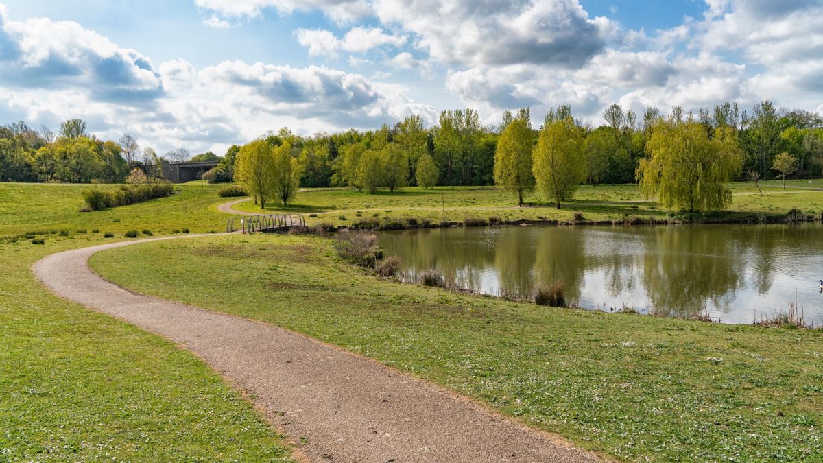 Pathway along Milton Keynes lake with blue sky and clouds