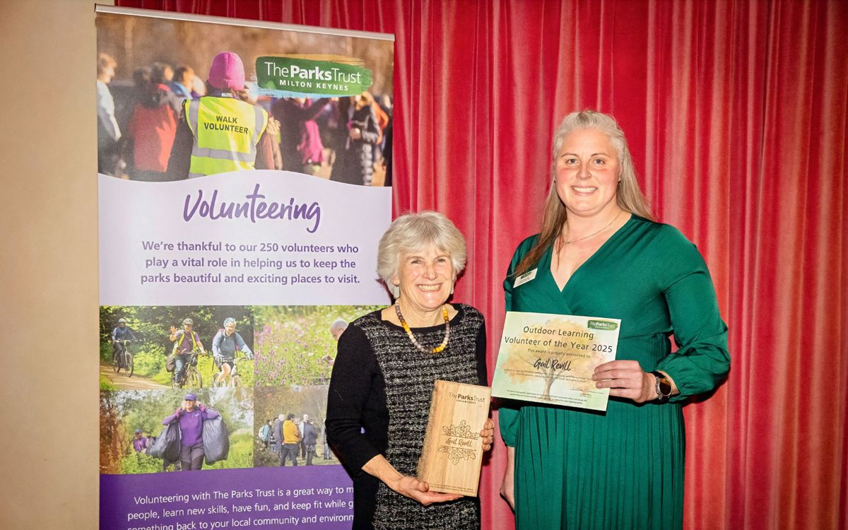 Two people smiling holding award and trophy