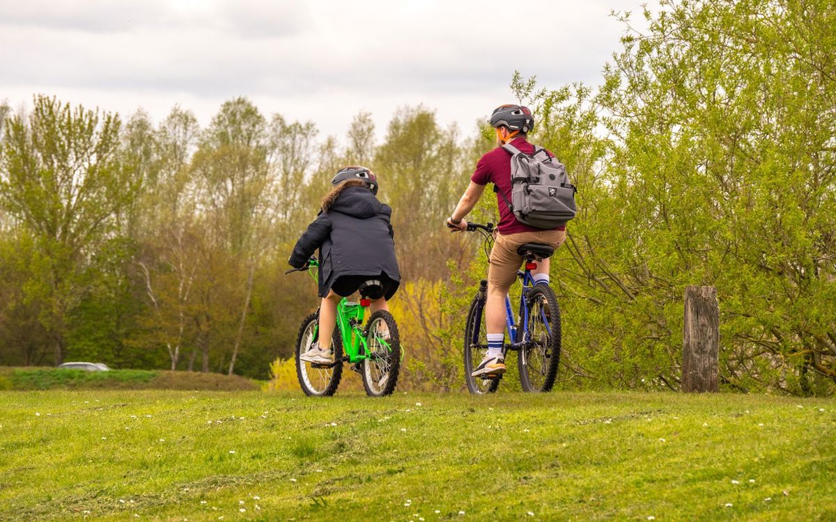 Two people cycling around Willen Lake with trees in the background