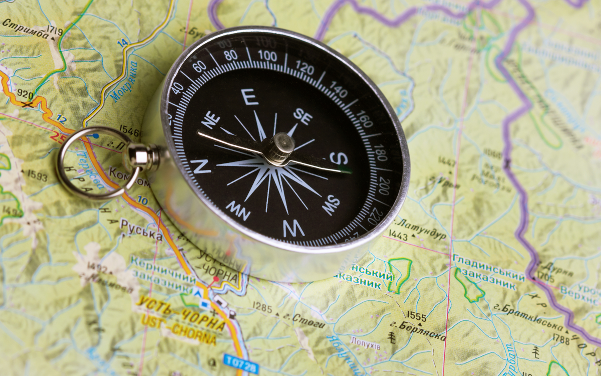 A metal compass lying on top of a map.