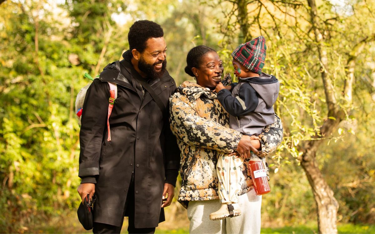 A family walking through an orchard smiling at eachother.