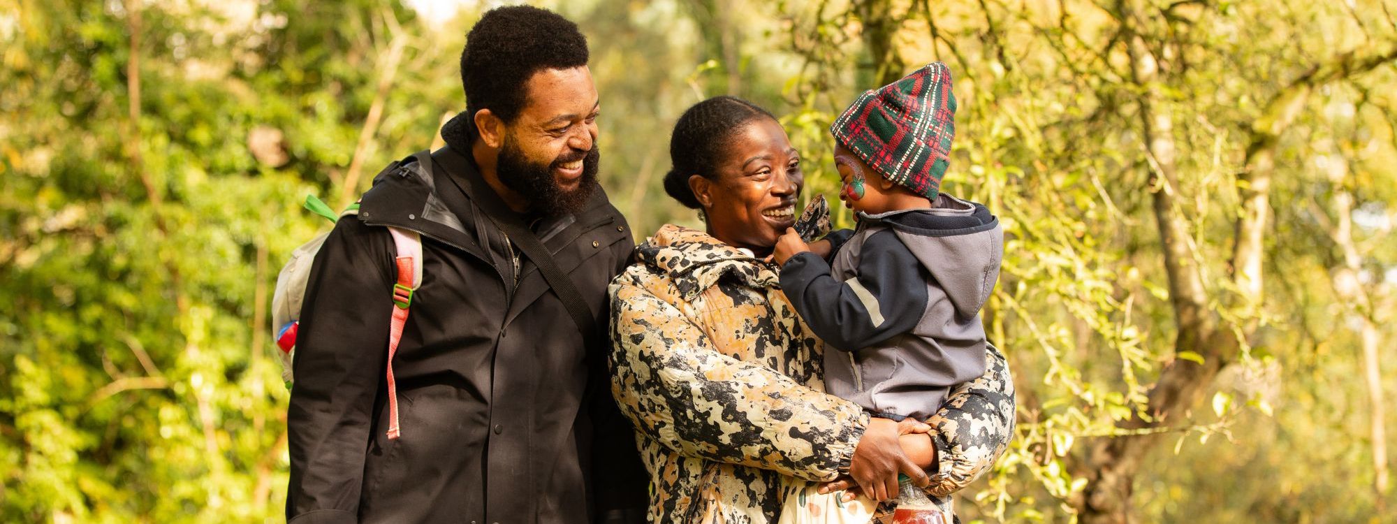 A family walking through an orchard smiling at eachother.