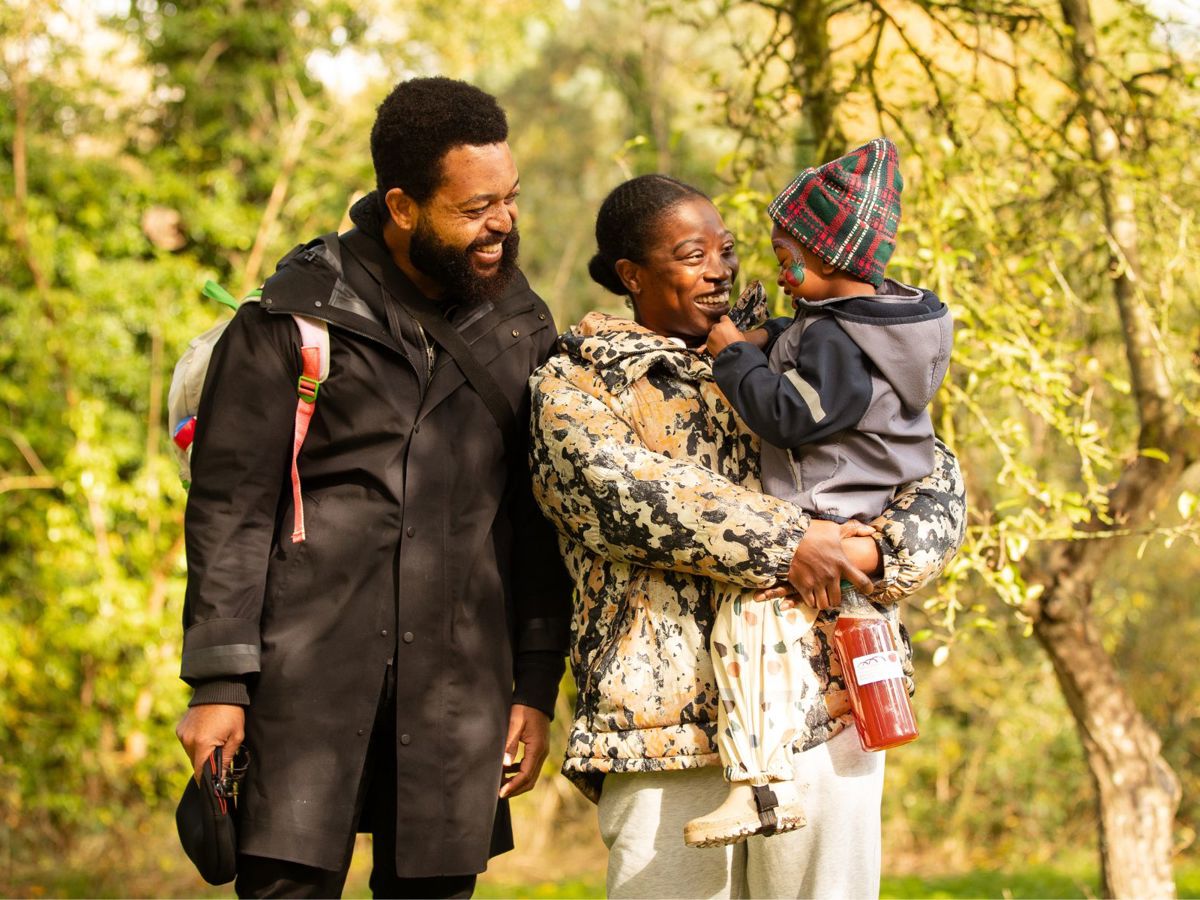 A family walking through an orchard smiling at eachother.