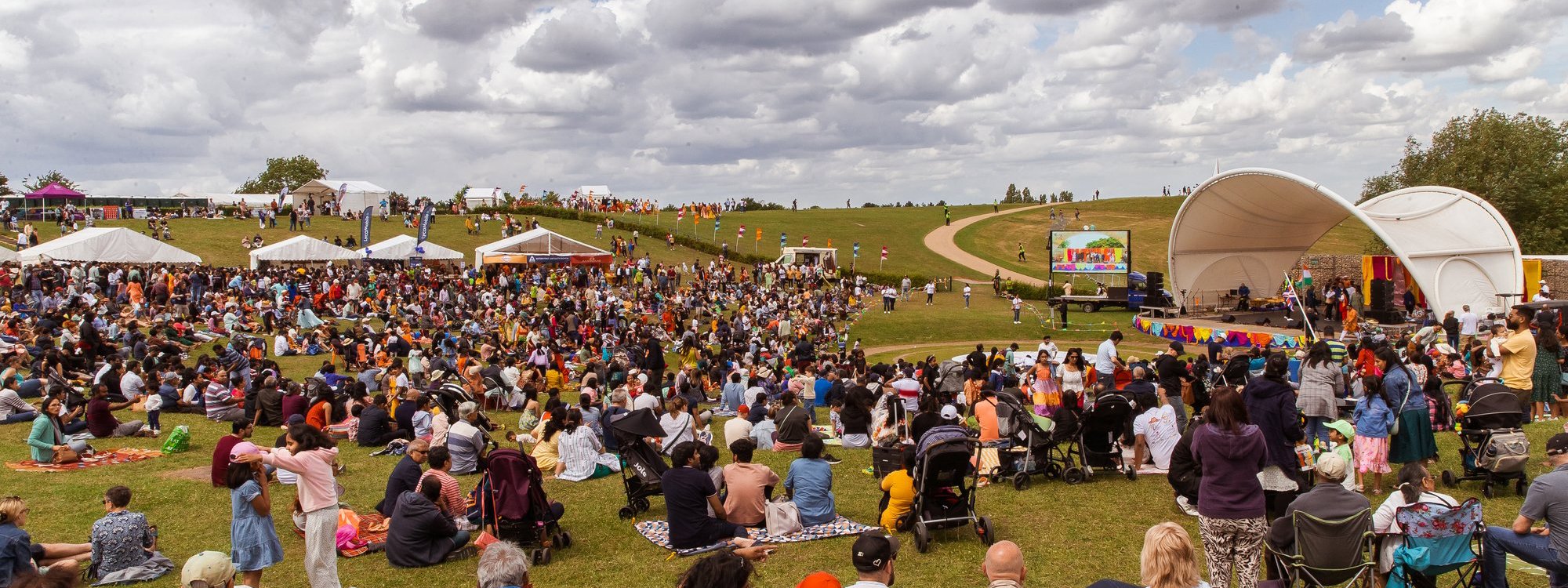 Pople sat on the grass facing the Campbell Park Amphitheatre, watching performances on the stage