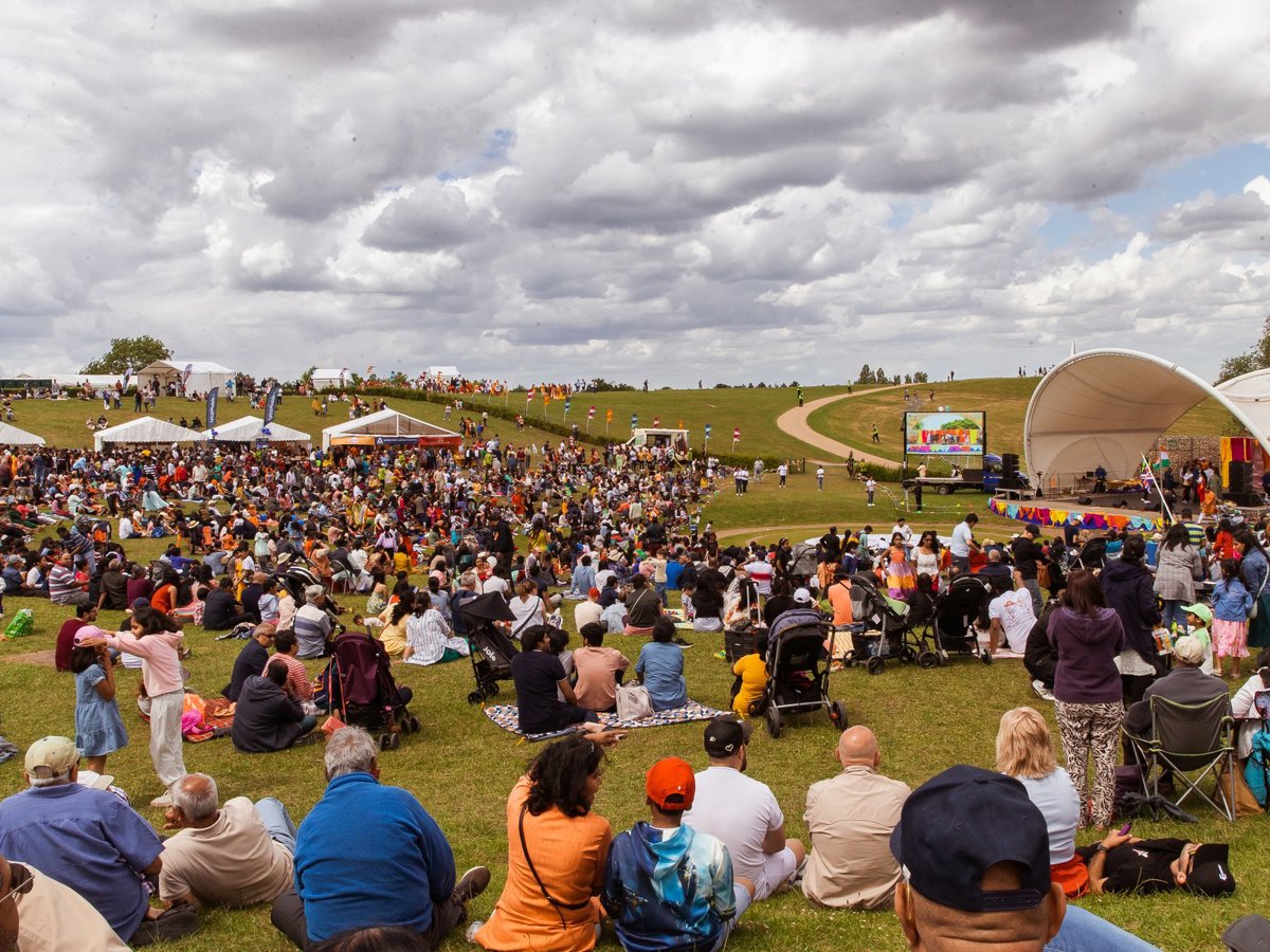 Pople sat on the grass facing the Campbell Park Amphitheatre, watching performances on the stage