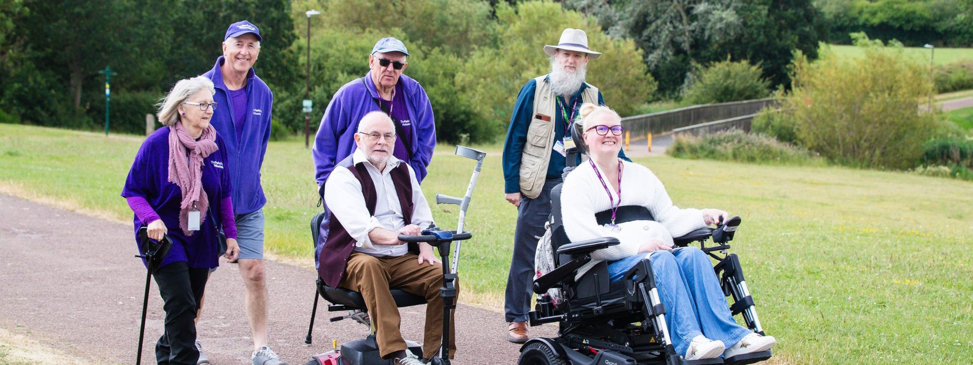 Group of travelling along on path in purple uniform and two in wheelchairs