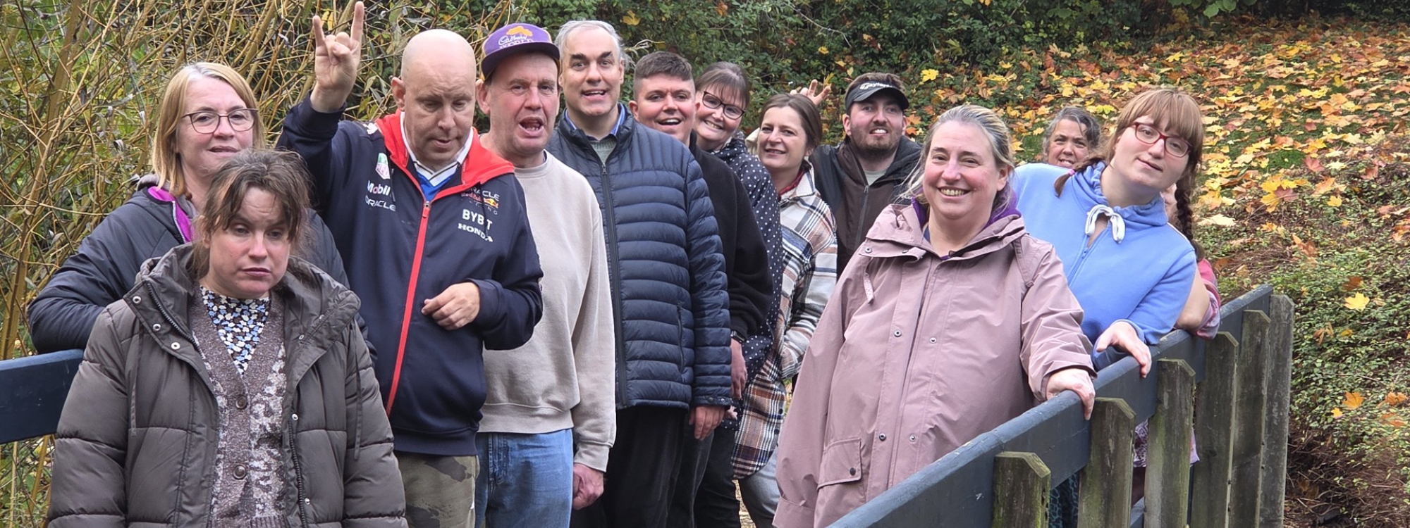 A group of people from Camphill Community on a walk. Posed on a bridge in a parkland location