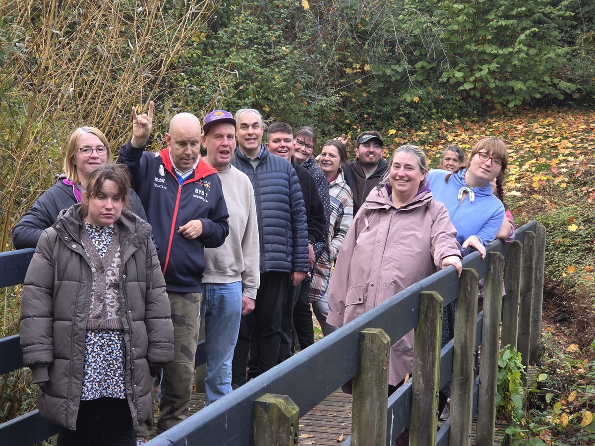 A group of people from Camphill Community on a walk. Posed on a bridge in a parkland location