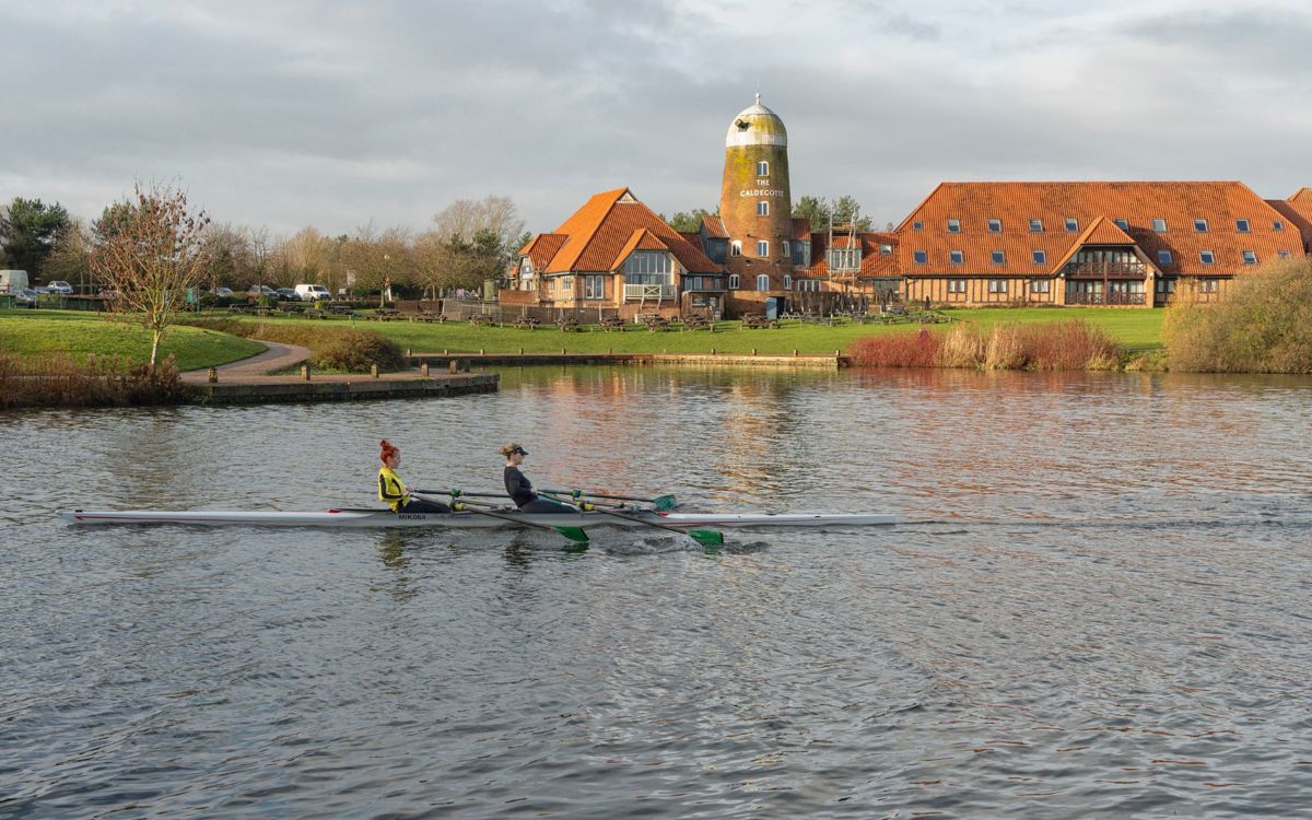 Two people rowing on Caldecotte Lake with Windmill in the background