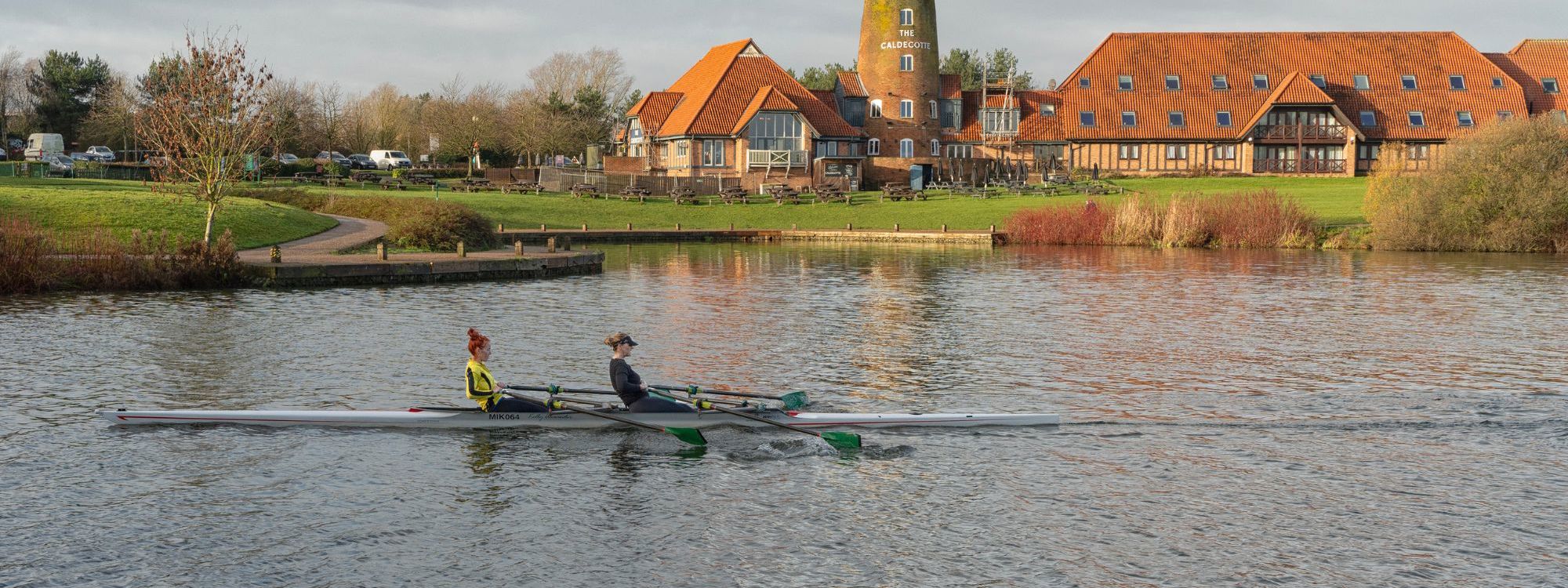 Two people rowing on Caldecotte Lake with Windmill in the background