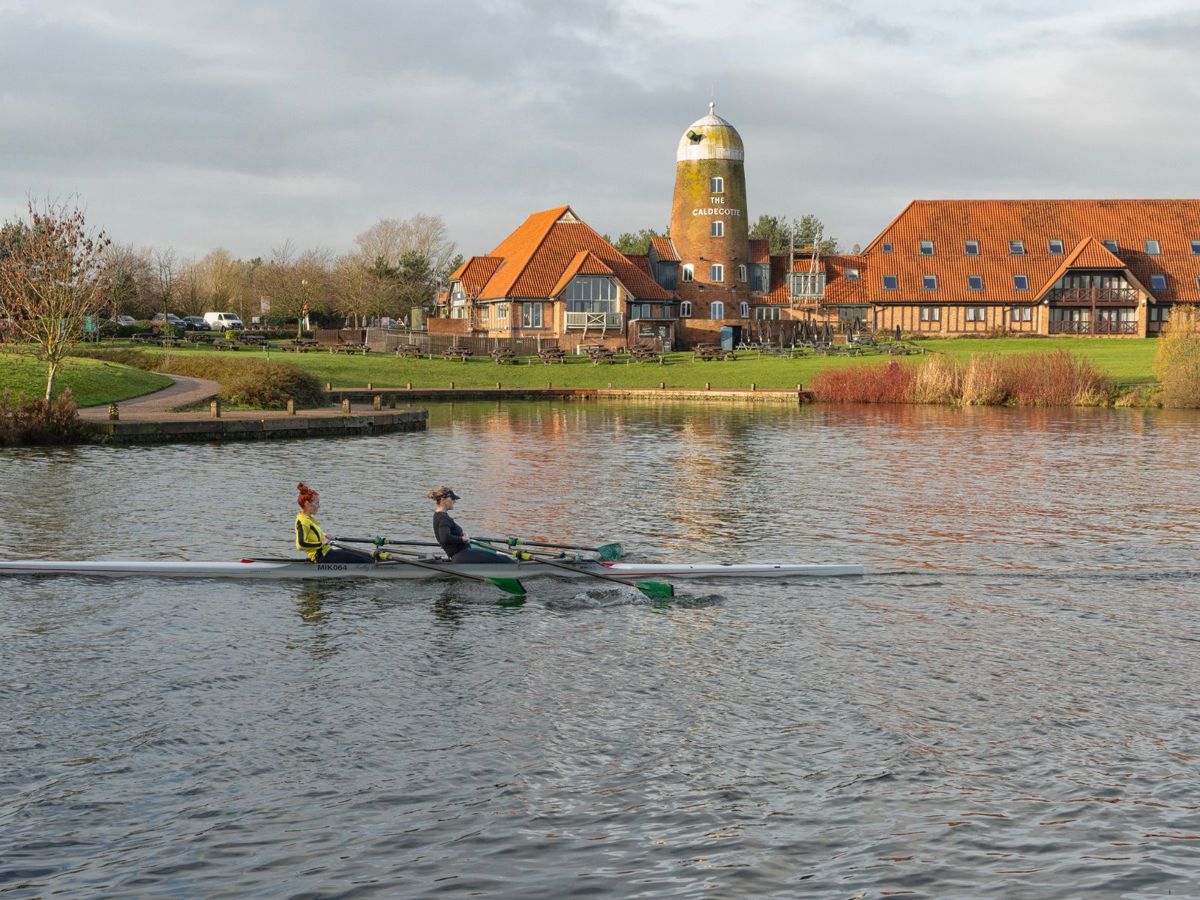 Two people rowing on Caldecotte Lake with Windmill in the background