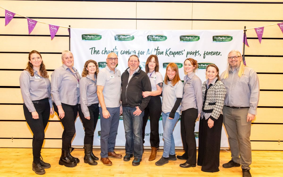 Group photo of Parks Trust staff members in uniform in front of photo wall