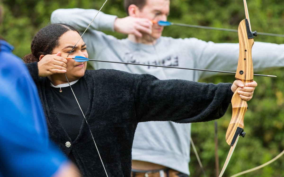 People aiming bow and arrow at archery session