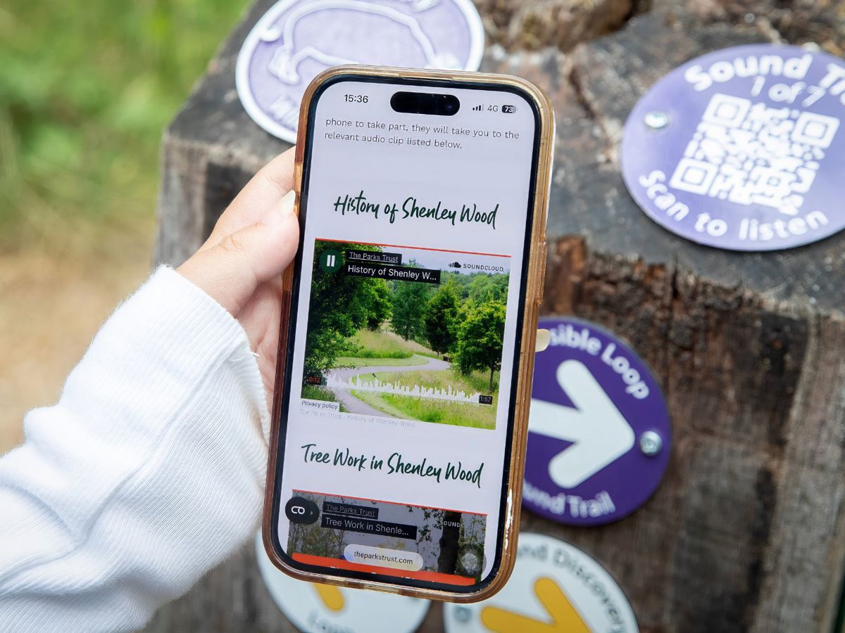 Hand holding phone on Sound Trail webpage on The Parks Trust website