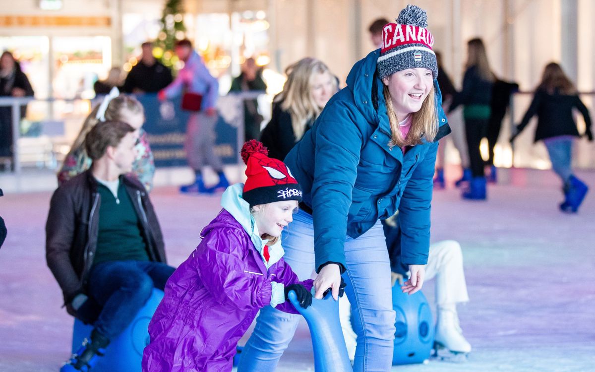 Adult helping child with skating aid at Willen On Ice