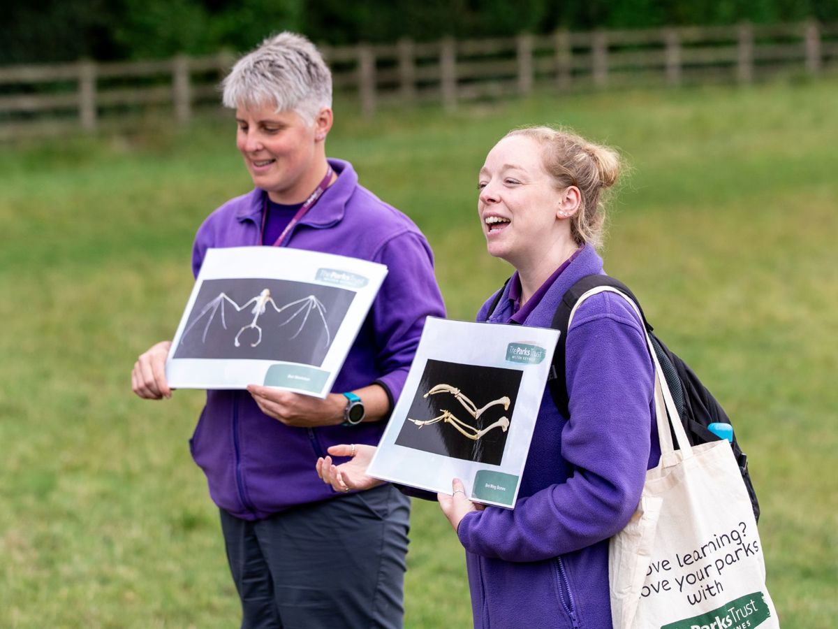 Two Parks Trust Outdoor Learning Leaders holding teaching resources in the park