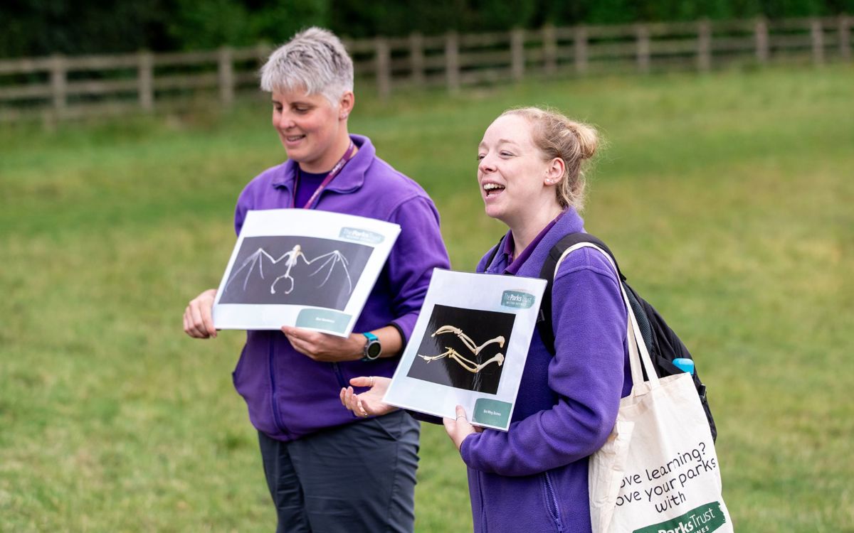 Two Parks Trust Outdoor Learning Leaders holding teaching resources in the park
