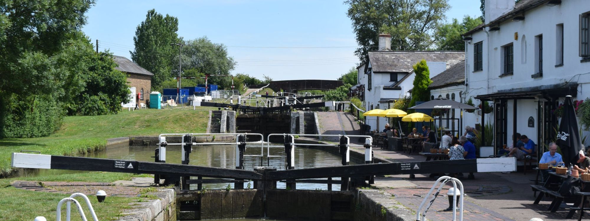 Image or Canal locks, sunny day, café on the side of the canal with people sitting outside