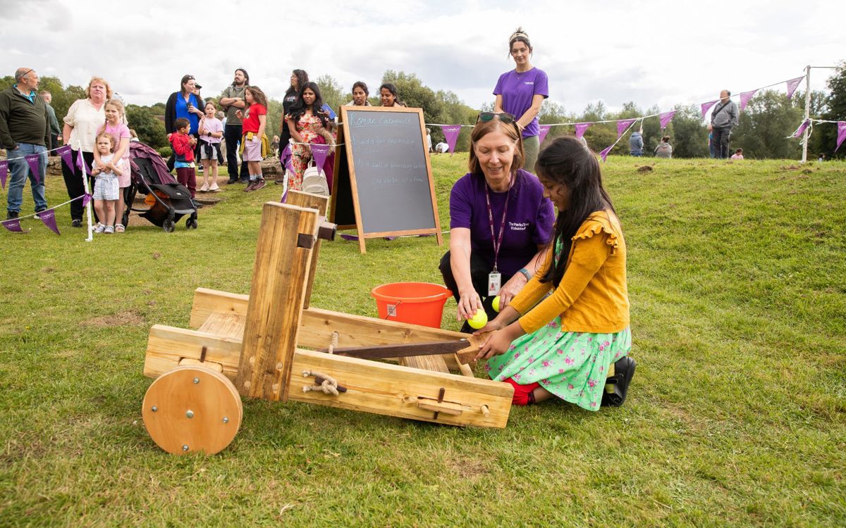 Volunteer Helping With Catapult At Roman Day event