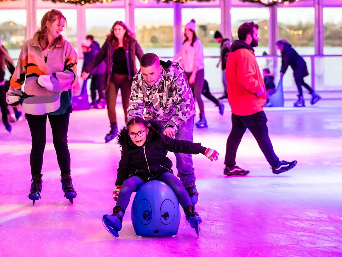 Parenting pushing child on skating aid at Willen On Ice