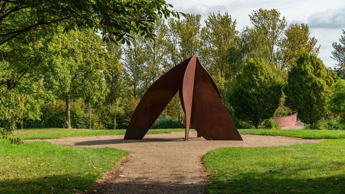 Head sculpture in Campbell Park with canal bridge in background
